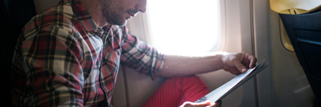 Tips for Long Haul Flights - man reading on plane